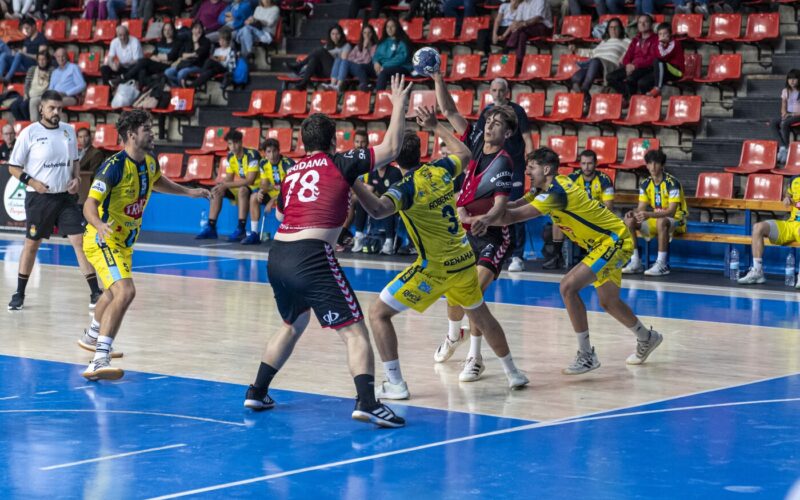 Jugador del Bm. Burgos pasando el pase al su pivote entre defensores del Trops Málaga